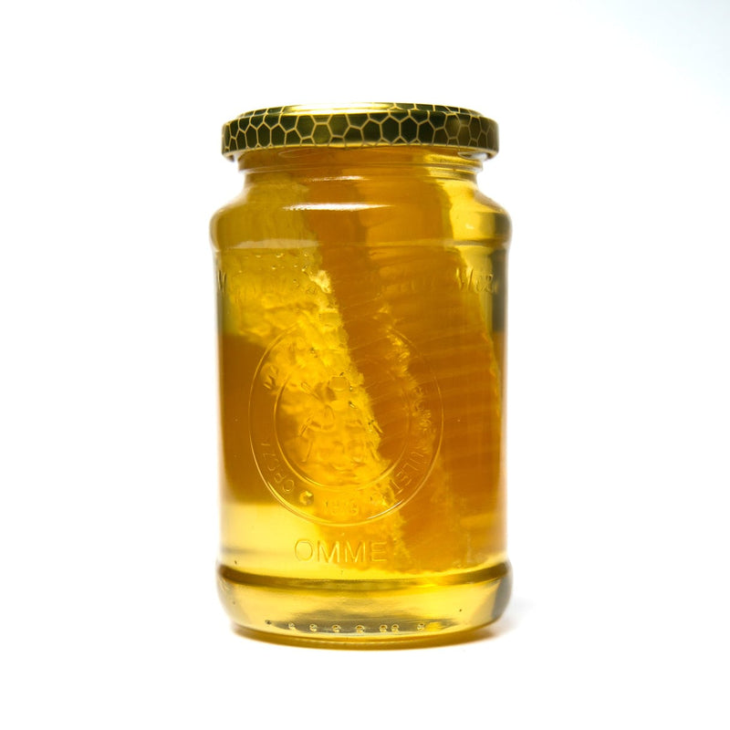 Glass jar of Acacia honey with a honeycomb chunk