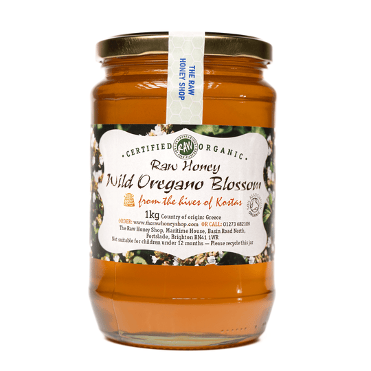 Large labelled glass jar containing 1kg of amber coloured raw organic wild oregano blossom honey.