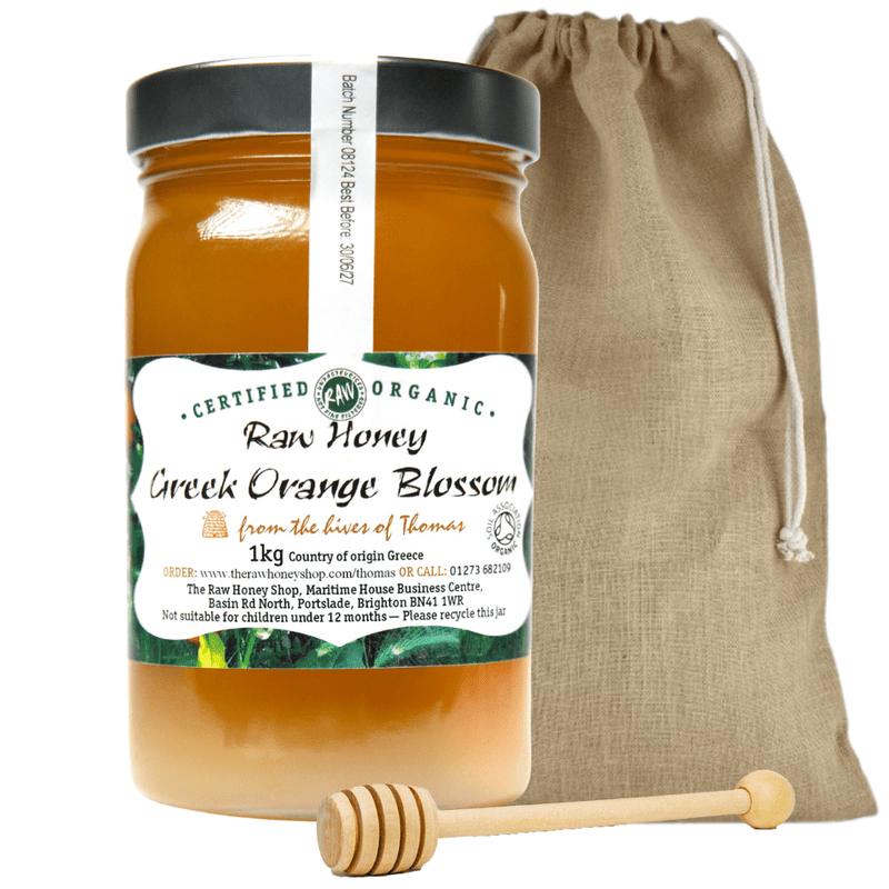 Large labelled glass jar containing 1kg of raw organic Greek orange blossom honey with jute drawstring bag and wooden honey dipper.