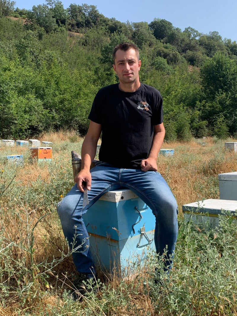 Beekeeper Dimitris sitting on one of his hives.