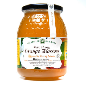 Large glass jar containing 1kg of pale orange coloured raw organic orange blossom honey